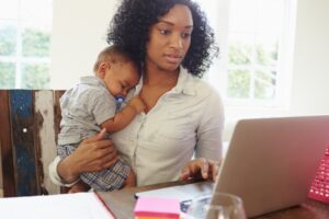 woman-holding-baby-while-researching-on-computer