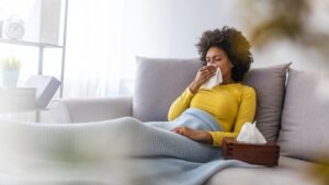 woman-sitting-on-couch-blowing-nose